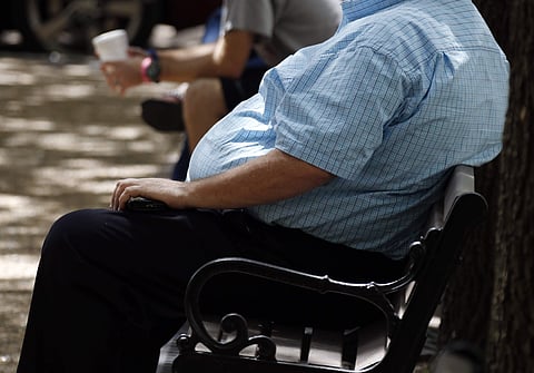 A heavy set man rests on a bench | AP