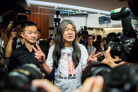 Pro-democracy lawmaker Leung Kwok-hung (C), also known as 'long hair', gestures as he leaves the legislature Council meeting in Hong Kong on July 14 after a verdict was handed down invalidating his oath, which was taken last year. (Photo | AFP)