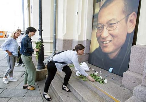 People place flowers and light candles in front of a picture of Liu Xiaobo, placed outside the Nobel's Peace center in Oslo, Thursday, July 13, 2017.  (Audun Braastad/NTB scanpix via AP)
