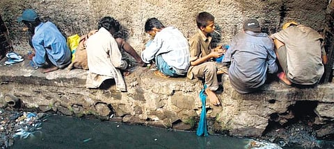 Drug addicts, including children, getting their fix along a drain