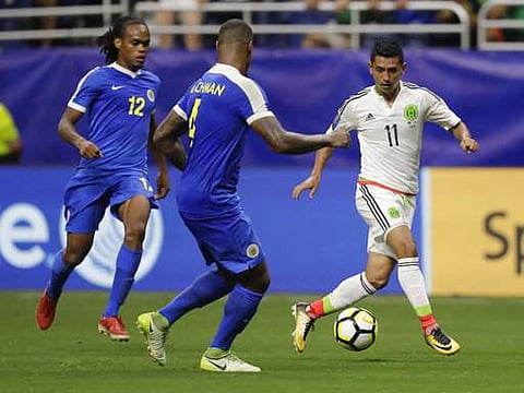 Mexico's Elias Hernandez (11) moves the ball past Curacao's Darryl Lachman (4) and Shanon Carmelia (12) during a CONCACAF Gold Cup soccer match in San Antonio. | AP