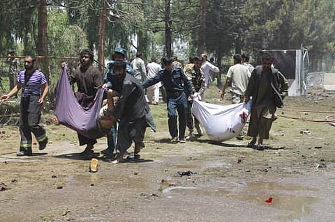 Afghans carry the bodies of men at after a suicide car bombing in Helmand province southern of Kabul. | AP