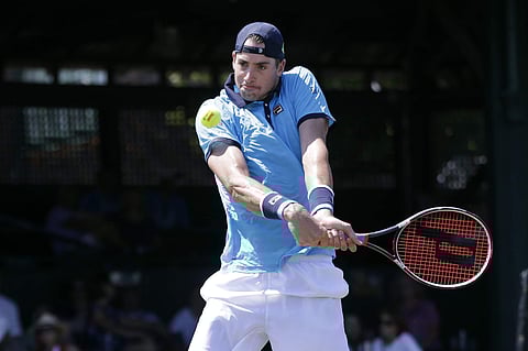 Top seed John Isner returns the ball to Dennis Novikov in their quarterfinal match at the Hall of Fame Tennis Championships. | AP
