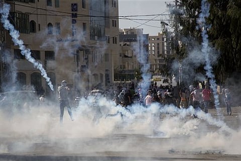 Palestinian protesters run for cover from tear gas fired by Israeli soldiers during clashes with Israeli troops near Ramallah, West Bank. |AP