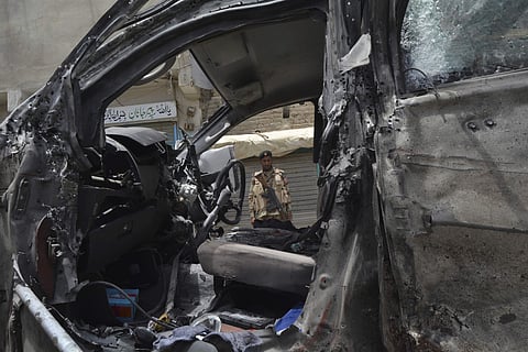 A Pakistani security officer looks at a vehicle that was targeted by a suicide attacker. | AP