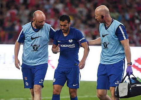 Chelsea forward Pedro Rodriguez (C) leaves the field after a collision with Arsenal's David Ospina during their pre-season football match in Beijing's National Stadium. | AFP