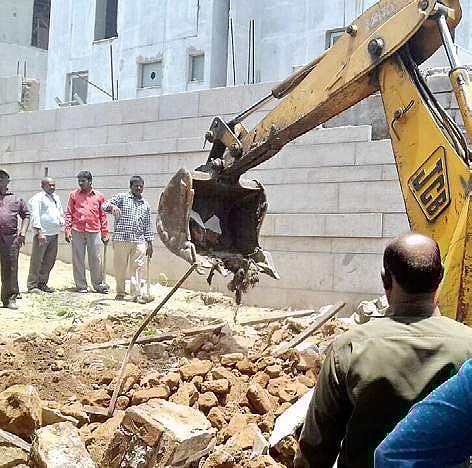 GHMC workers trying to demolish a compound wall of a house in Hyderabad on Monday| Express PHOTO