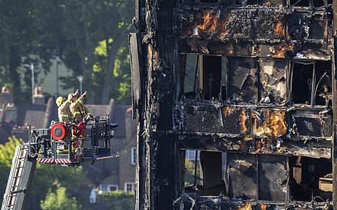 Firefighters survey the damage to the fire-gutted Grenfell Tower in London, Friday, June 16, 2017, after a fire engulfed the 24-story building Wednesday morning. London firefighters combed through the burned-out public housing tower Thursday in a grim sea