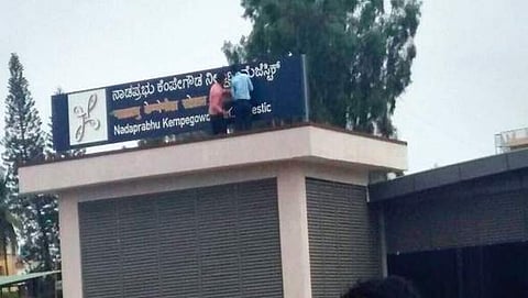 A Hindi signboard being covered up at a Bengaluru Metro station