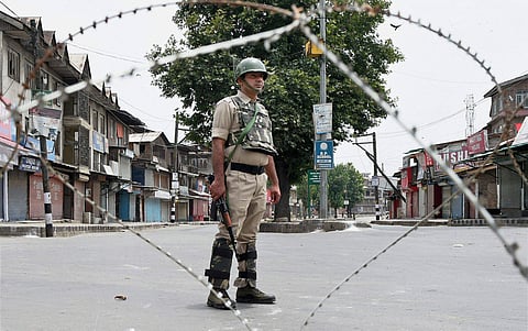 Security jawan stands guard during restrictions in down town Srinagar on Friday. Authorities imposed restrictions in parts of Srinagar as a precautionary measure ahead of slain Hizbul Mujahideen commander Burhan Wani's first death anniversary. | PTI