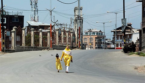 A woman and a child walk on a deserted street during restrictions imposed to maintain law and order problem following strike call given by Joint Hurriyat Leadership and all trade bodies against the proposed abrogation of article 35-A in Srinagar on Saturd