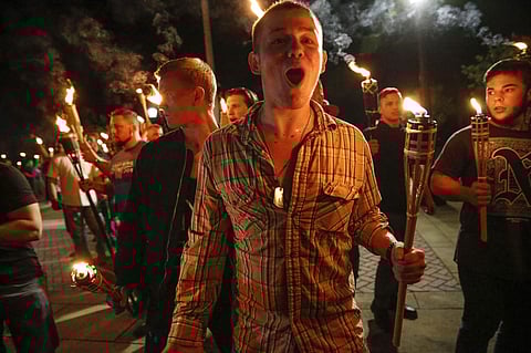 In this photo taken Friday, Aug. 11, 2017, multiple white nationalist groups march with torches through the UVA campus in Charlottesville, Va. Hundreds of people chanted, threw punches, hurled water bottles and unleashed chemical sprays on each other afte