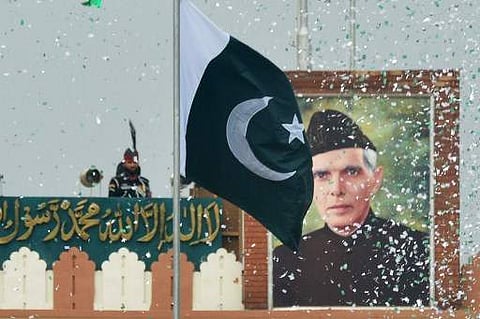 The portrait of Muhammad Ali Jinnah is seen at at the India-Pakistan Wagah border post as a Pakistani Ranger (top) unfurls the Pakistani national flag (AFP)