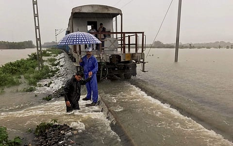 A goods train halts on the flooded tracks as railway empolyees inspect the damaged embankment along the Katihar-Guwahati line in Katihar district of Bihar on Monday.  (PTI)