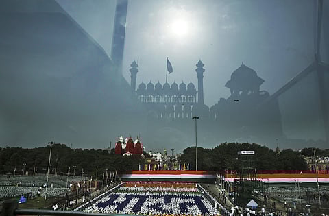 Red Fort monument is reflected on the bullet proof glass covering the podium from where Indian Prime Minister Narendra Modi is scheduled to deliver an Indian Independence Day speech as schoolchildren wearing different colors form a representation of the n