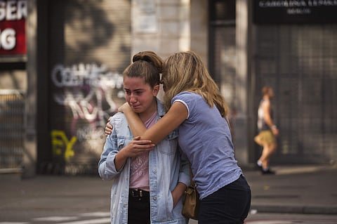 Two women cry at a memorial tribute in Las Ramblas, after a terror attack that killed 14 people and wounded over 120 in Barcelona, Spain. | AP