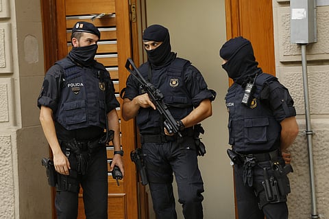 Police officers stand outside a building during a search in Ripoll, north of Barcelona. | AP