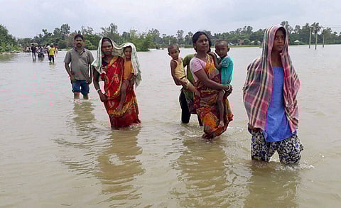 Village women carry their children through flood water on the way to nearby relief camp at Flood hit Malda district of West Bengal. | PTI