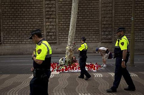 Police officers walk past candles and flowers placed on the ground. (AP Photo)