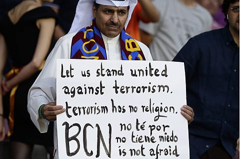 A Barcelona fan holds a sign against terrorism and in support of the victims of the van attacks before a La Liga soccer match between Barcelona and Betis at the Camp Nou stadium in Barcelona, Spain, on Sunday. Words at bottom in Catalan, Spanish and Engli