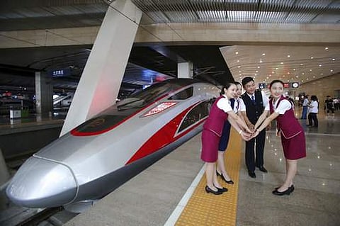 Railway workers pose for photos with the Fuxing, China's latest high speed train capable of reaching 400kph during its maiden service from Beijing.|AP