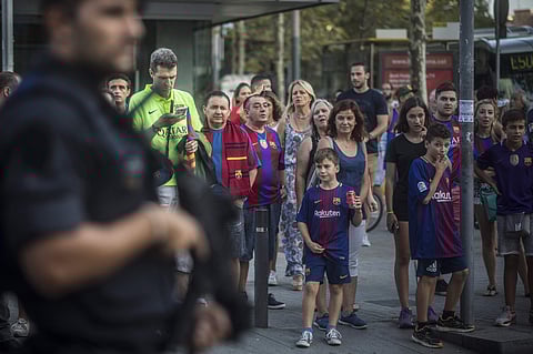 Fans look at an armed police officer near the stadium before a La Liga soccer match between Barcelona and Betis at the Camp Nou stadium in Barcelona. | AP