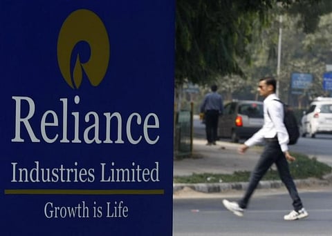 A man walks past a Reliance Industries Limited sign board installed on a road divider in Gandhinagar. (File photo | Reuters)