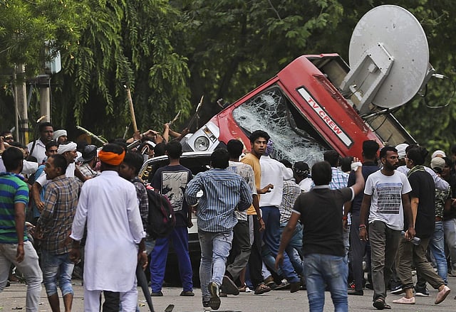 Dera Sacha Sauda sect members overturn an broadcast van of a TV news channel on the streets of Panchkula. (Photo | AP)
