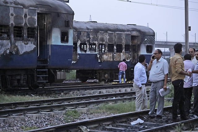 People stand near vandalised train coaches in New Delhi. Mobs rampaged across Panchkula on Friday after the court verdict. (Photo | AP)