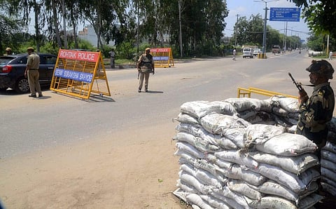 Personnel of Para-Military force stand guard an entry point of Rohtak on Sunday. | PTI