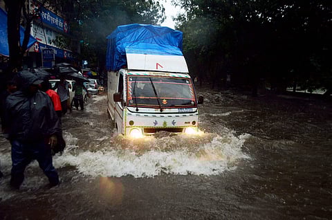 Vehicles wade through waterlogged street after heavy rains at Thane in Mumbai on Tuesday. | PTI