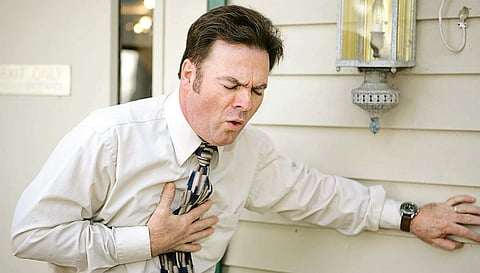 A representative picture of a middle aged man outside his office suffering from a persistent cough.