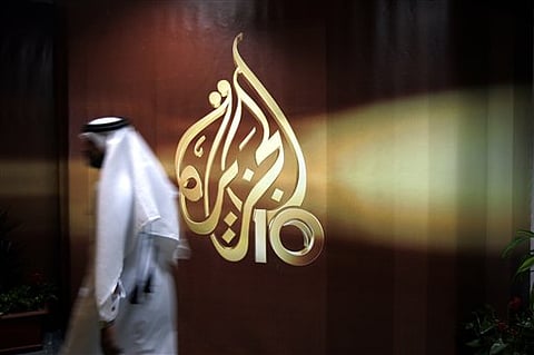 a Qatari employee of Al Jazeera Arabic language TV news channel walks past the logo of Al Jazeera in Doha. (AP Photo, File)
