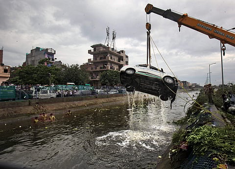 A car being pulled out of a canal as the rescue operations are underway after a part of the Ghazipur garbage landfill collapsed in east Delhi on Friday afternoon. | PTI