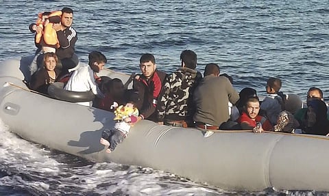 In this Friday, Sept. 8, 2017 video frame grab image, made available by Turkey's Coast Guard Saturday, Sept. 9, 2017, a Syrian migrant among others, briefly lifts a small child, on a rubber dinghy. | AP