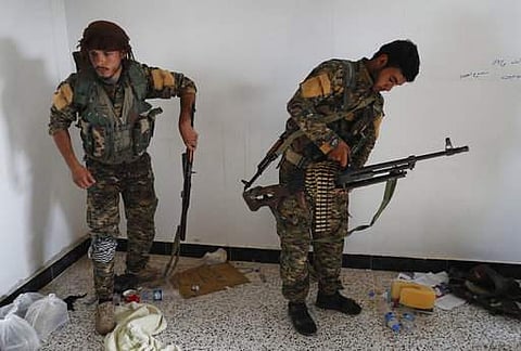 An Arab fighter (L) and Kurdish fighter (R), who fight together with the US-backed Syrian Democratic Forces (SDF), hold their weapons as they prepare to move to the front line to battle against the Islamic State militants (AP)