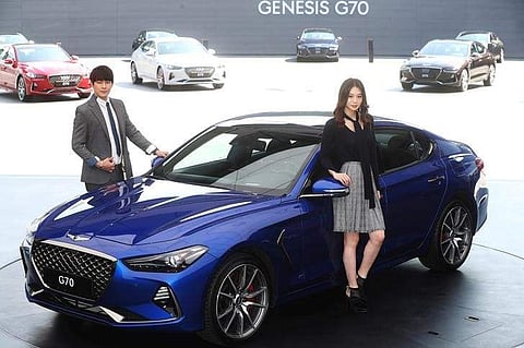 Models pose for photographs with a Genesis G70 during its unveiling ceremony in Namyangju, South Korea, September 15, 2017. | Reuters