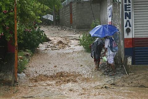 People walk under a downpour on a flooded street in Acapulco, Guerrero state, Mexico, Thursday, Sept. 14, 2017. Hurricane Max hit Mexico's southern Pacific coast. | AP
