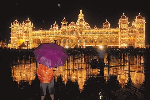 The reflection of the beautifully illuminated palace in rain water in Mysuru on Sunday evening People perform Yoga in front of the palace in Mysuru . | s Udayshankar