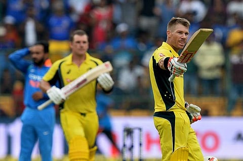 Australian cricketer David Warner (R) raises his bat while his partner Aaron Finch looks on to celebrate his century (100 runs) during the fourth one day international (ODI) match against India. | AFP