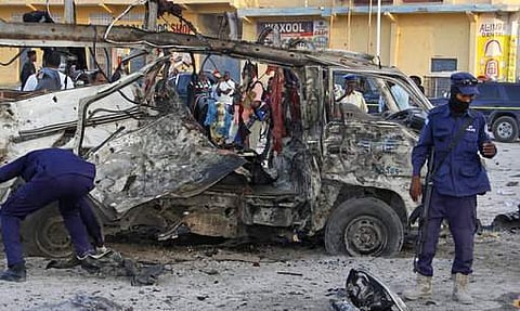 Security forces stand near the wreckage of a minibus at the scene of a car bomb attack in Mogadishu, Somalia. | AP