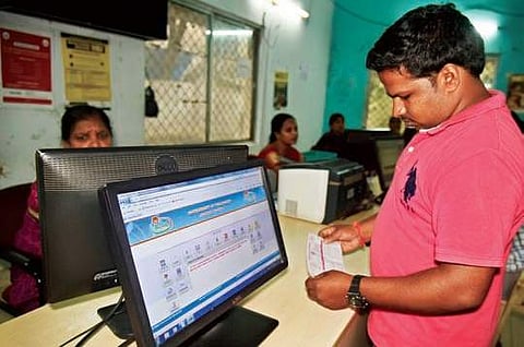 A man cross checking his receipt after paying bills at a Mee Seva centre in Hyderabad on Friday | vinay madapu
