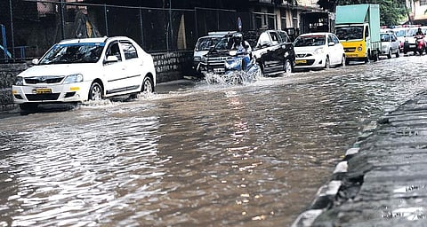 Vehicles wade through a waterlogged street after heavy rains in Bengaluru . | EPS