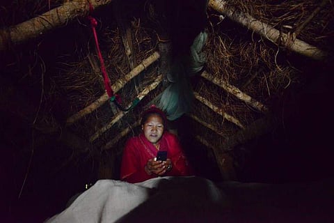 In this photograph taken on February 3, 2017, Nepalese woman Pabitra Giri looks at her mobile in a Chhaupadi hut during her menstruation period in Surkhet District, some 520km west of Kathmandu. (Photo | Associated Press)