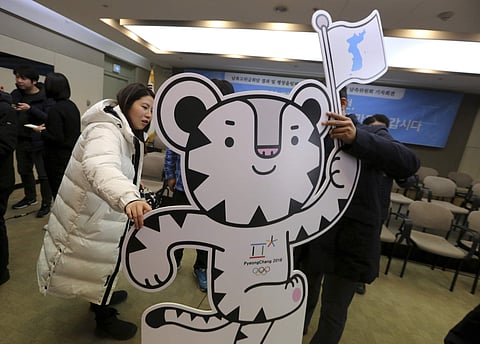 Protesters hold a cutout of an official mascot of the 2018 Pyeongchang Olympic Winter Games, white tiger 'Soohorang', with a reunification flag during a press conference to welcome the outcome of a meeting between South and North Korea, Thursday, Jan. 11,