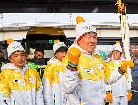 South Korean football legend Cha Bum-Kun (C) carries the Olympic flame during the PyeongChang 2018 Torch Relay near the World Cup Stadium in Seoul on January 13, 2018 | Photo: AFP
