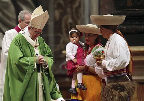 A family walks on the altar in front of Pope Francis on the occasion of a Mass on the world day for migrants and refugees | AP
