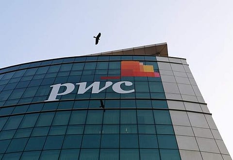 A bird flies past the logo of Price Waterhouse installed on the facade of its office in Mumbai. | REUTERS