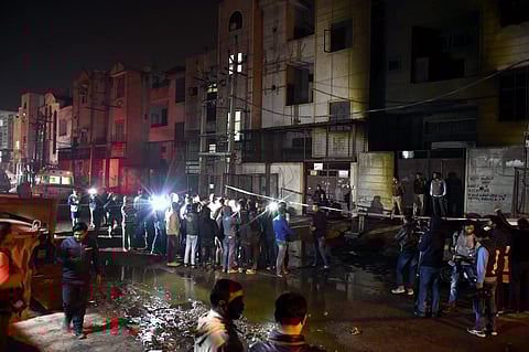 Fire fighters and media outside the two-storey cracker factory which caught fire in north Delhi's Bawana Industrial Area on Saturday. | PTI