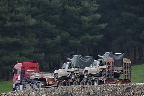 A truck, part of a convoy, carrying military pickup trucks with machine guns attached is seen on the outskirts of the village of Sugedigi, Turkey | AP